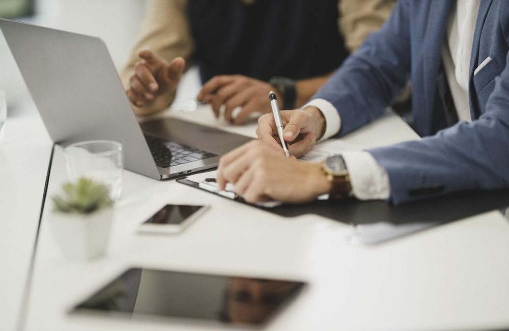 Free close up of two people hands, signing documents with laptop on table in office image, public domain CC0 photo.
